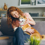 a woman sitting on a couch holding a dog