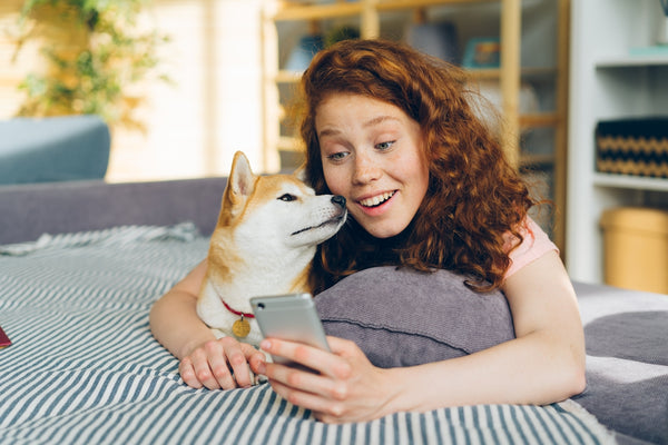 a woman laying on top of a bed next to a dog