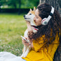 a woman sitting on the grass with a dog and headphones
