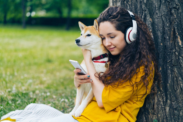 a woman with headphones is holding a dog