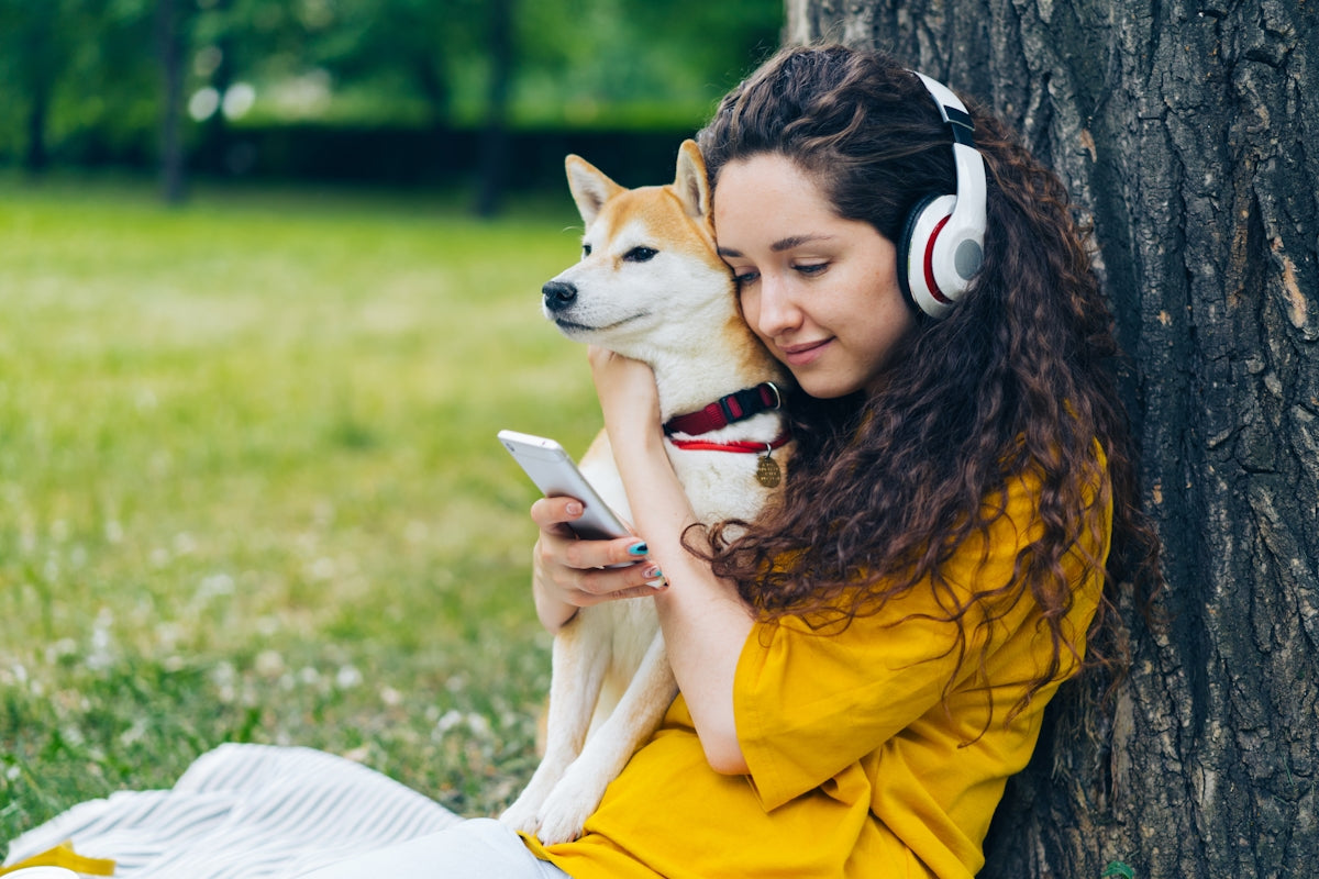 a woman with headphones is holding a dog