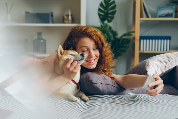 a woman laying on a bed holding a dog
