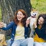 two women sitting next to a tree with a dog