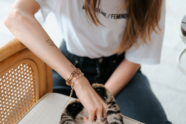 A woman petting a cat on the back of a chair