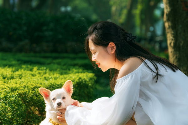 A woman kneeling down next to a white dog
