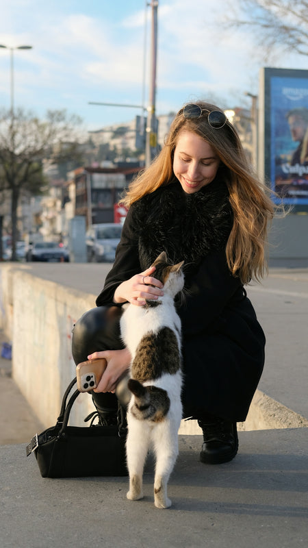 A woman is petting a cat on the street