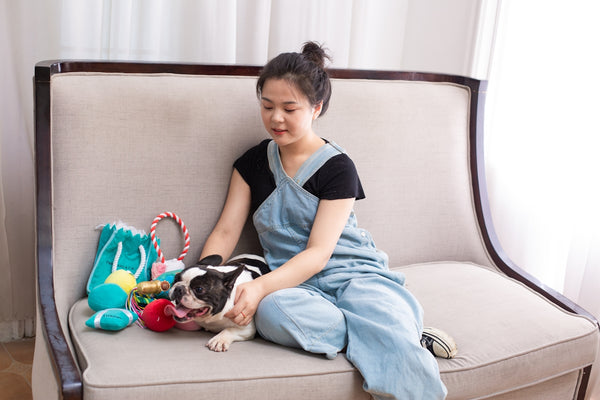 Woman cuddles with a dog on a couch.