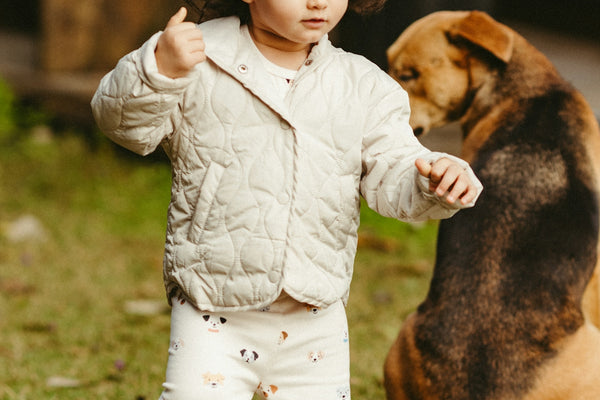 A child plays while a dog watches nearby.